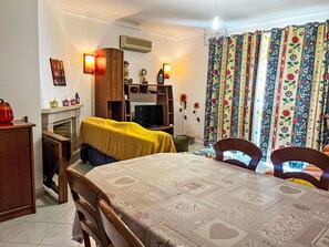 A cozy living room with a fireplace, a dining table, and a TV. - Apartment with Pool View by Interhome (Quarteira)