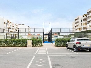 A parking lot with a car, a pedestrian crossing, and a building entrance with a glass facade. - Apartment with Pool View by Interhome (Quarteira)