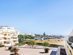 A residential area with modern buildings, a parking lot, and a clear view of the sea. - Apartment with Pool View by Interhome (Quarteira)