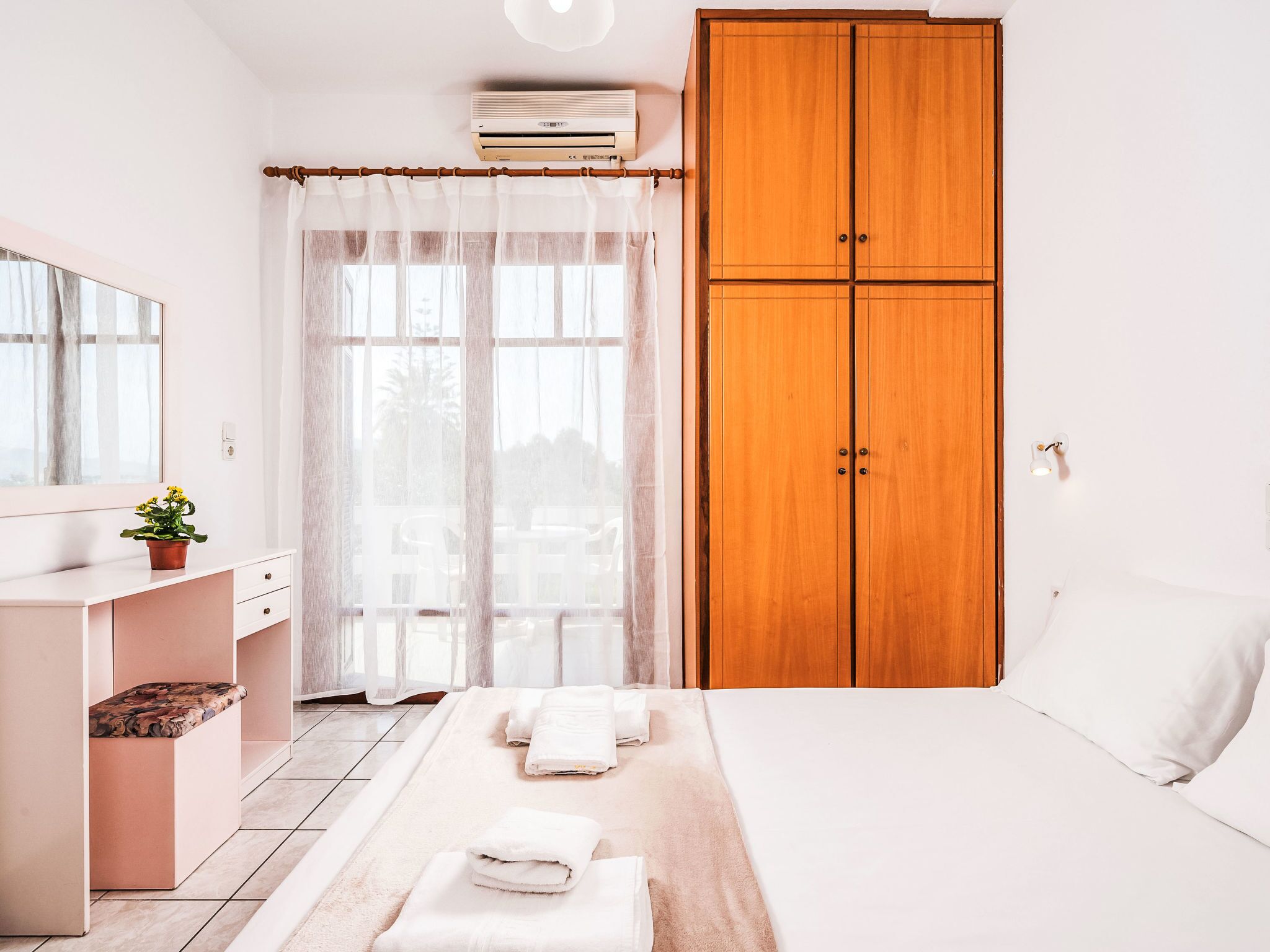 Een slaapkamer met een bed, een kledingkast, een bureau en een raam met gordijnen.