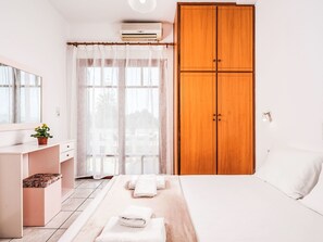 A bedroom with a bed, a wardrobe, a desk, and a window with curtains. - Apartment 7 with seaview and beautiful sunset by Interhome (Chania)
