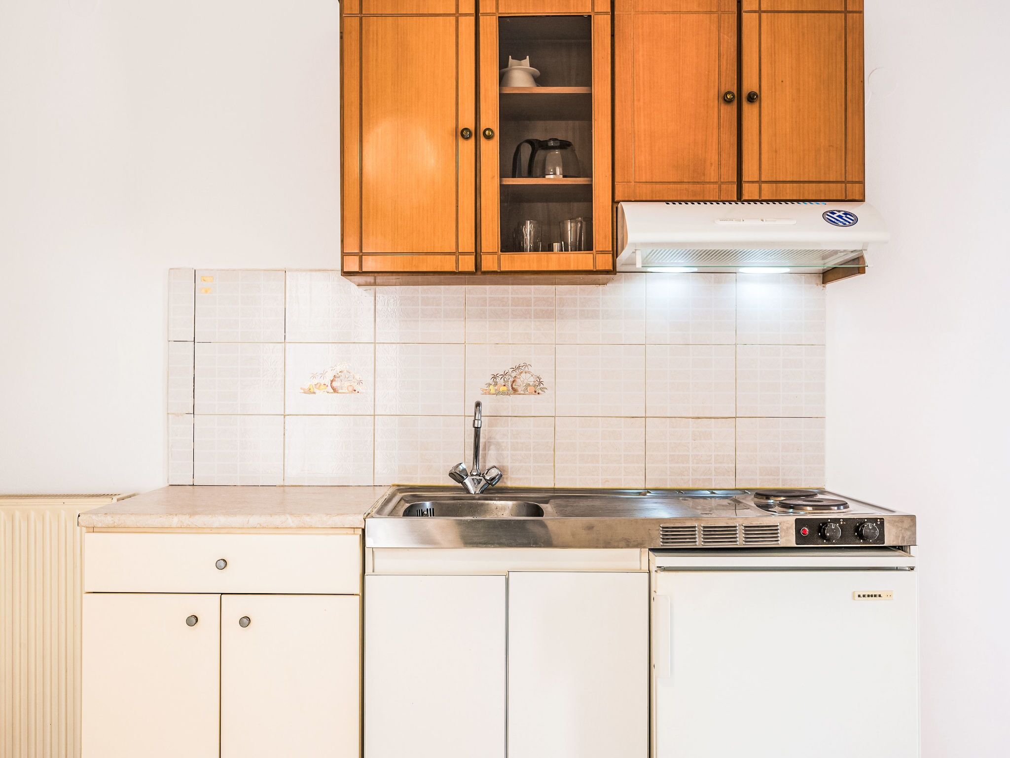 A kitchen with wooden cabinets, a stainless steel sink, and a stove.