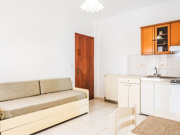 A compact living space with a sofa, a kitchenette, and a wooden door.