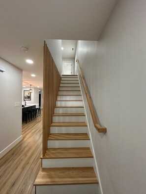 Eine Treppe mit Holzboden und Geländer führt zu einem Raum mit weißer Wand und einer Tür.