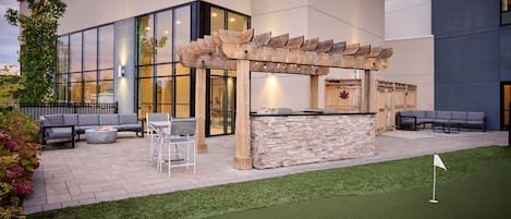 An outdoor patio with a stone bar, seating area, and artificial turf.