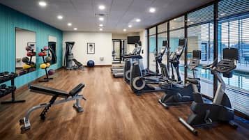 Una palestra con macchinari cardio, attrezzature per sollevamento pesi e una parete di specchi.