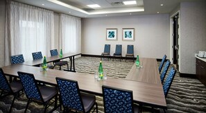 A conference room with a long table, chairs, and two framed artworks on the wall.