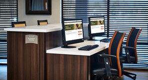A reception desk with two monitors, a keyboard, and office chairs in a modern office setting.