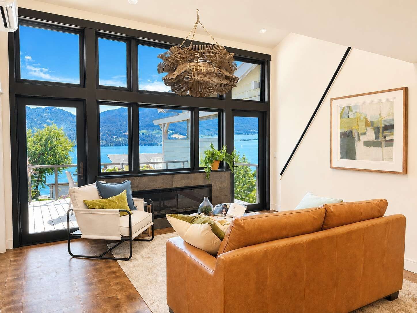 Ein modernes Wohnzimmer mit großem Fenster, Kamin, einer Couch und einer Pendelleuchte.