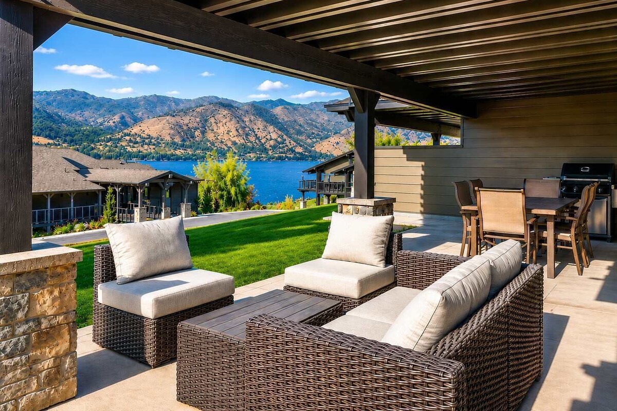 An outdoor patio with wicker furniture and a view of mountains and a lake.