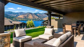 An outdoor patio with wicker furniture and a view of mountains and a lake.