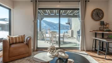 A living room with a sofa, a coffee table, and a view of a balcony with outdoor furniture.