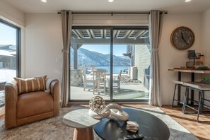 A living room with a sofa, a coffee table, and a view of a balcony with outdoor furniture.