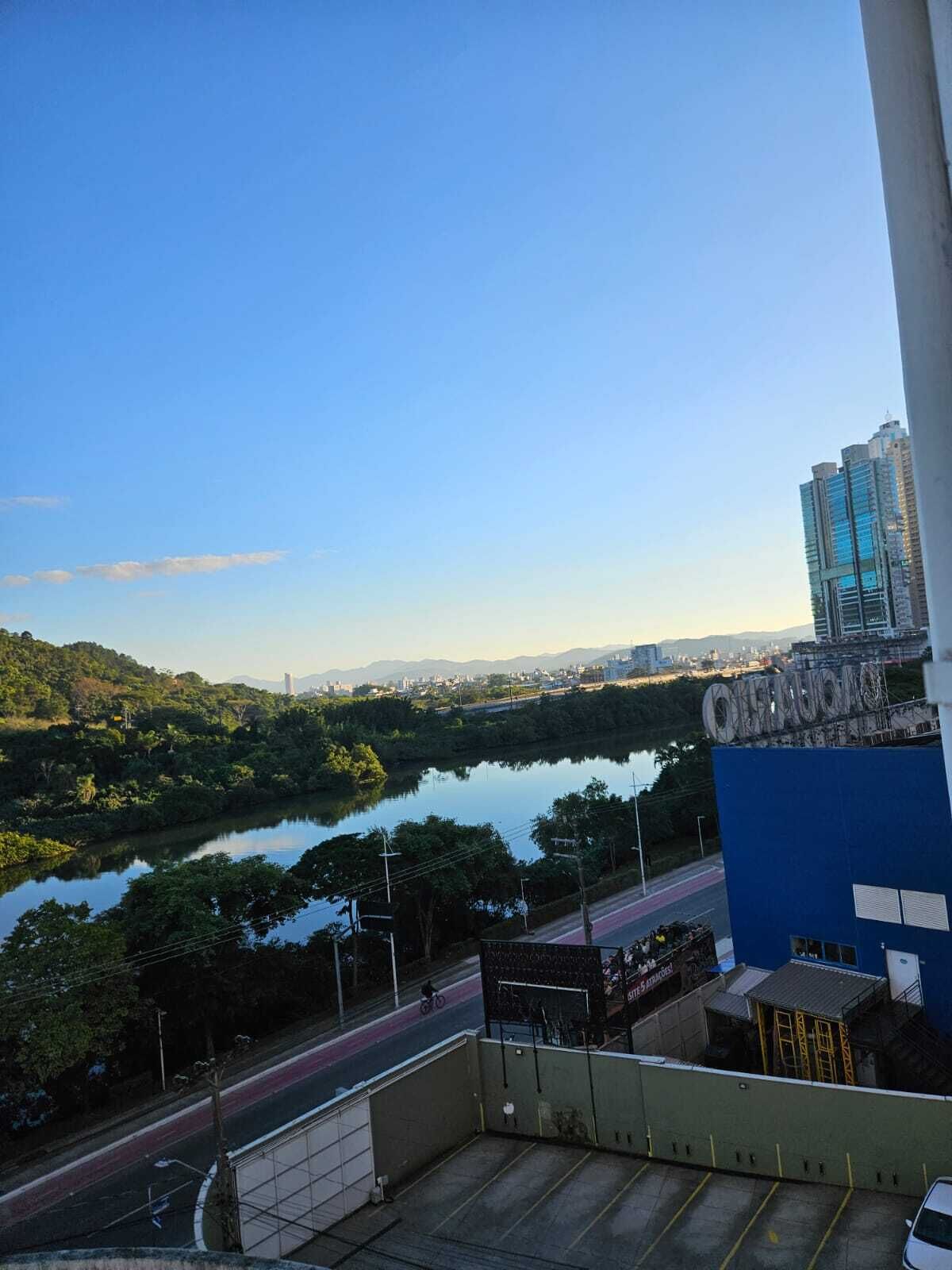 A view of a river with a bridge, a road, and a building with a blue facade.