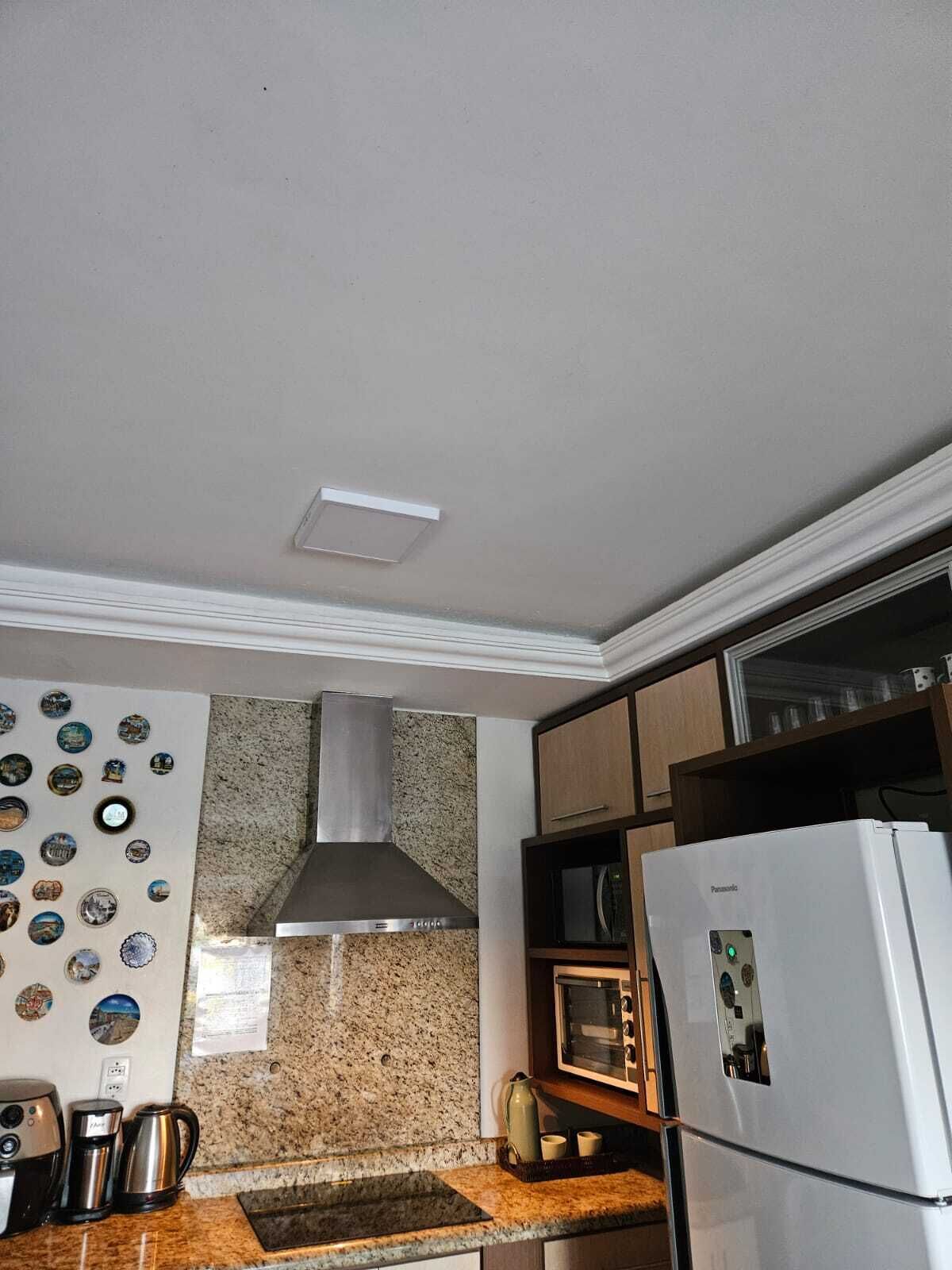 A kitchen with a stainless steel range hood, a white refrigerator, a microwave, and a coffee maker on the counter.