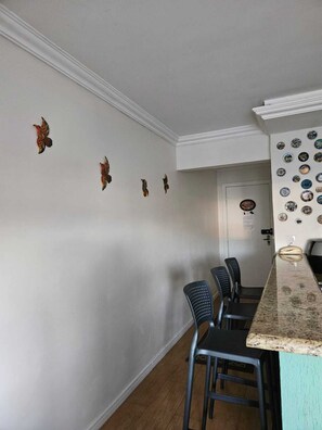 A kitchen with a marble countertop, black chairs, and decorative wall art. - Apartment right on the beach next to the aquarium. (Balneário Camboriú)