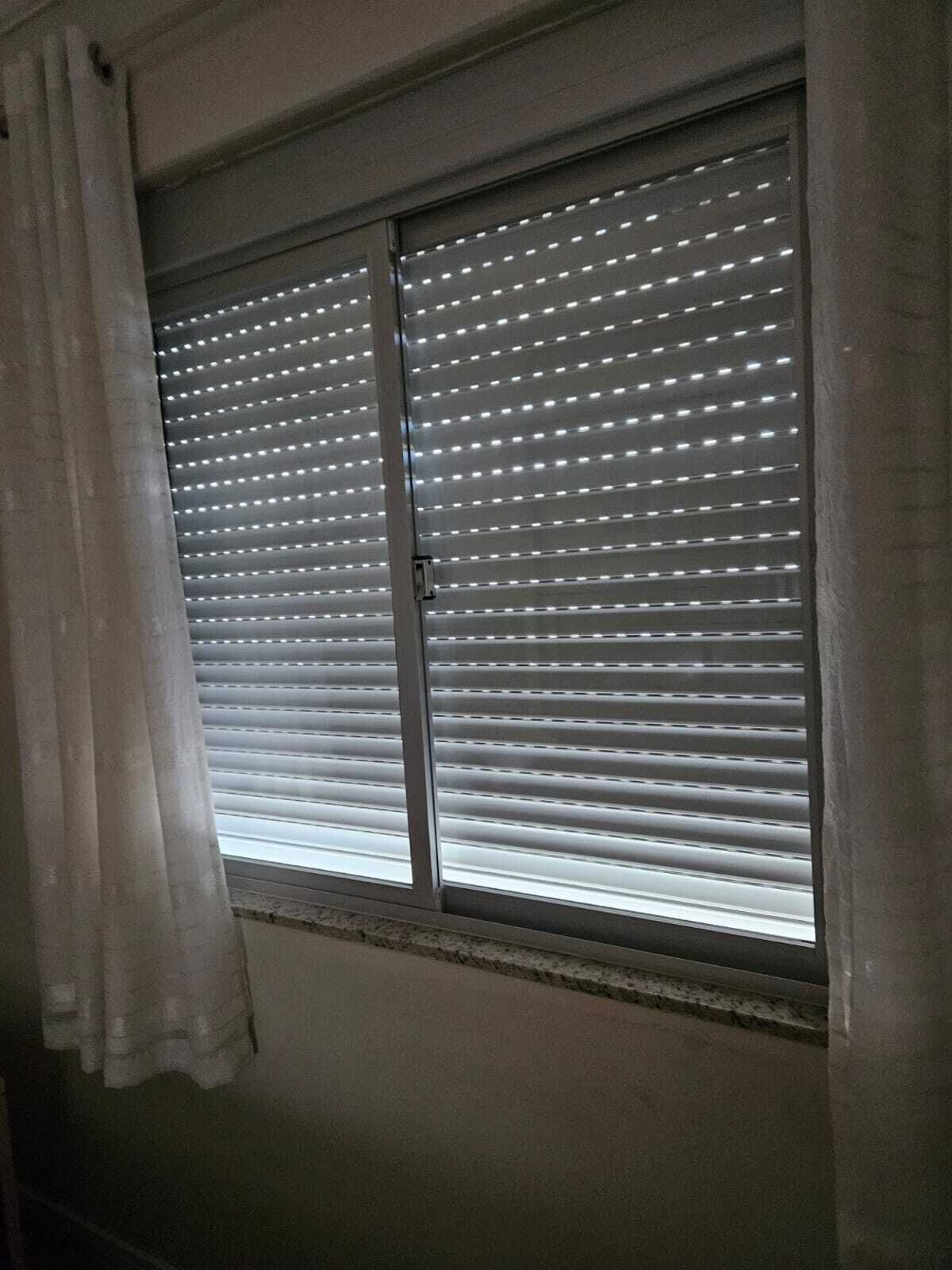 Ikkunassa on vaakasuorat sälekaihtimet, ja verho on osittain vedetty alas.