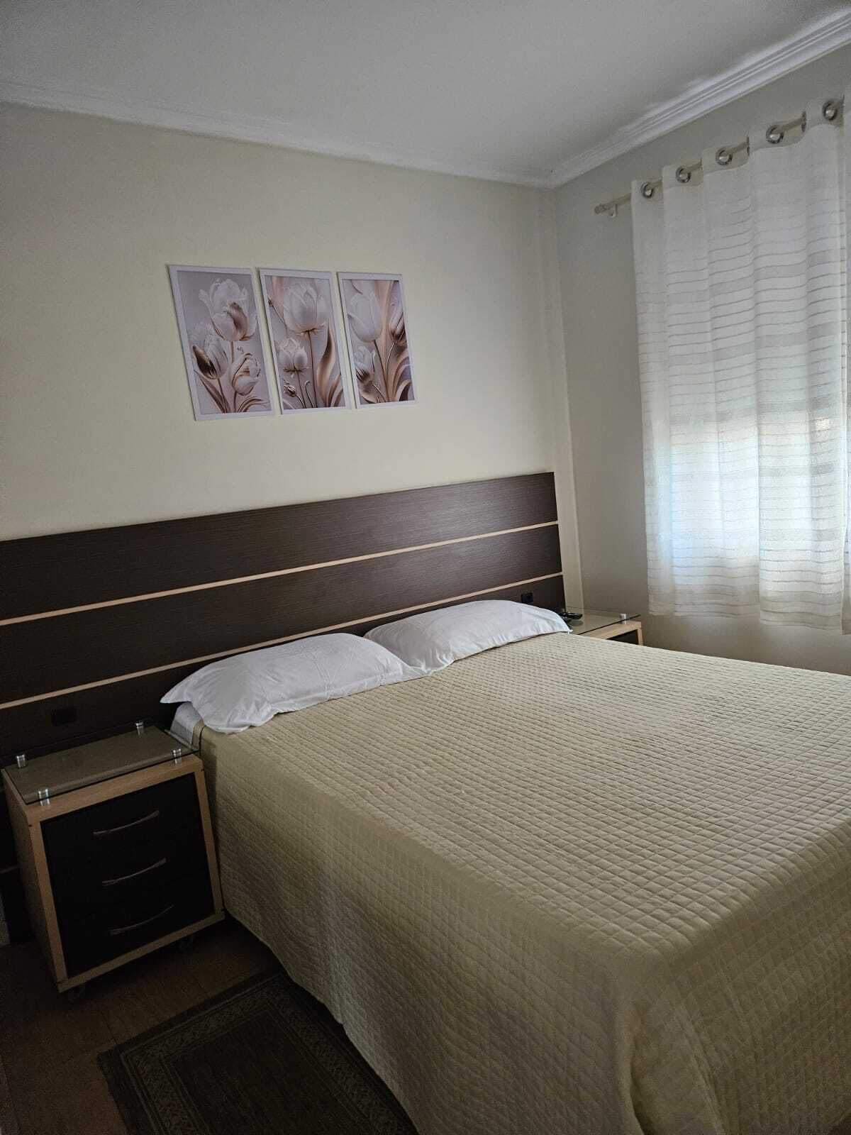 Habitació d'hotel amb un llit gran, dues taules de nit, un capçal de llit i una finestra amb cortines.