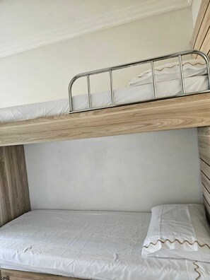 A bunk bed with a metal rail and a mattress with a white cover. - Apartment on the beachfront next to the Aquarium. (Balneário Camboriú)
