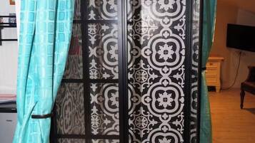A shower enclosure with a patterned curtain and a glass door.
