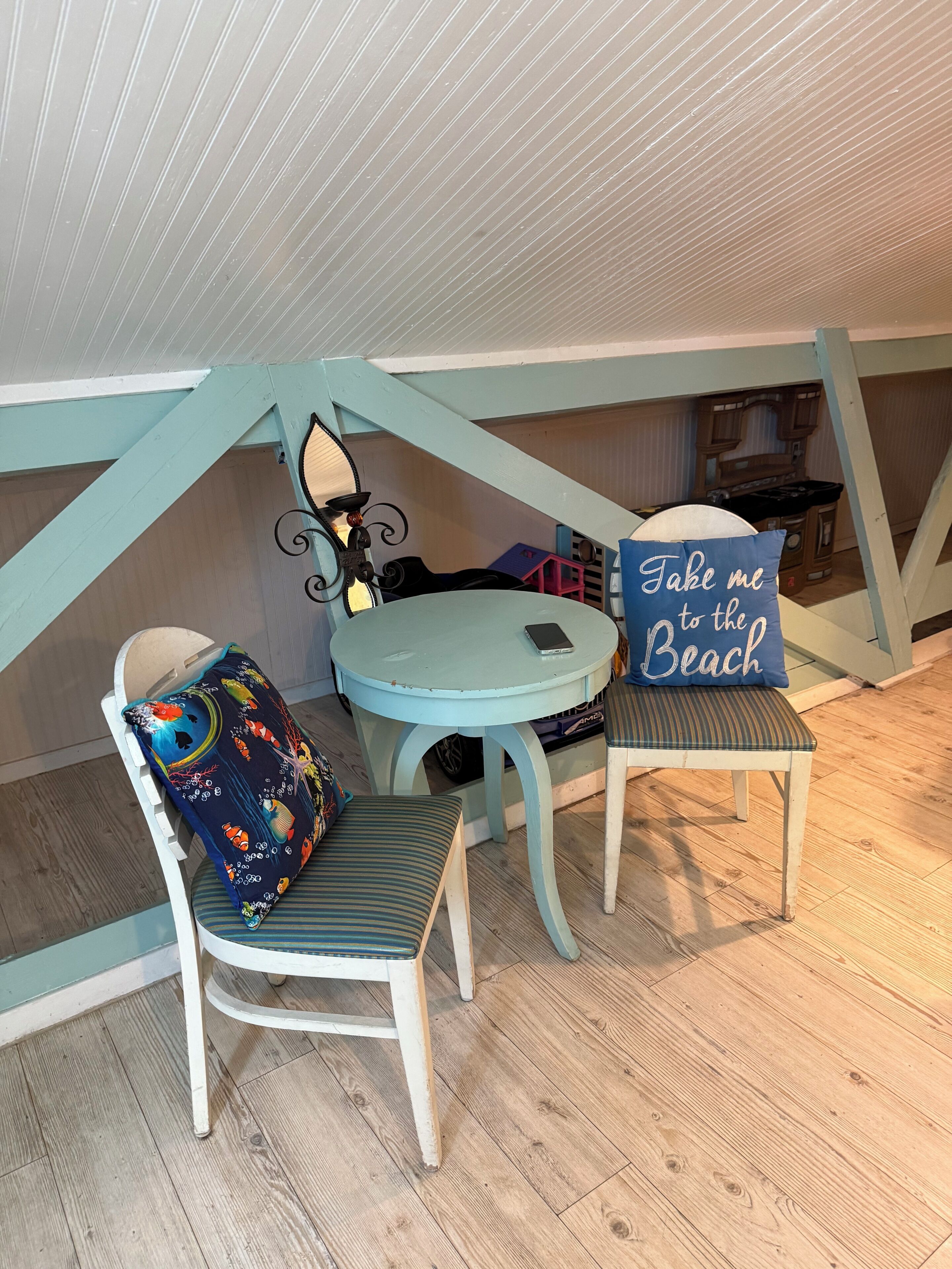 A cozy attic room with a round table, two chairs, and a ceiling fan.