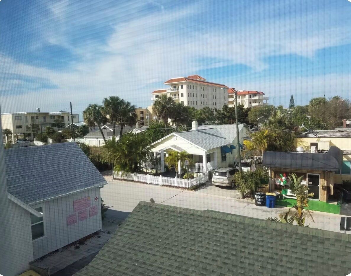 A residential area with a large building with a red roof, a white building with a sign, and a small structure with a green roof.