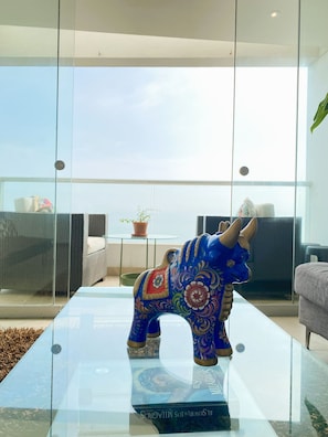 A blue ceramic elephant figurine on a glass table in a modern living room with a view. - Miraflores duplex with ocean view garage (Lima)