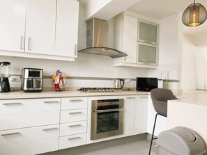 A modern kitchen with white cabinetry, stainless steel appliances, a gas stove, and a built-in oven. - Miraflores duplex with ocean view garage (Lima)