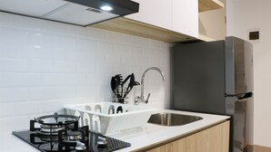 A modern kitchen with a gas stove, stainless steel sink, and a built-in refrigerator. - Pleasurable And Modern 2Br Tokyo Riverside Pik 2 Apartment (Teluknaga)