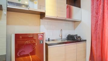 Cocina compacta con refrigerador, pileta y estufa.
