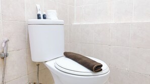Eine Toilette mit Handtuch auf dem Sitz, einer Toilettenpapierrolle und einer Flasche Handseife.