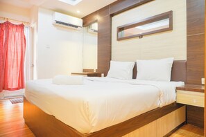 Quarto de hotel com uma cama grande, uma mesinha de cabeceira, um espelho e um aparelho de ar condicionado.