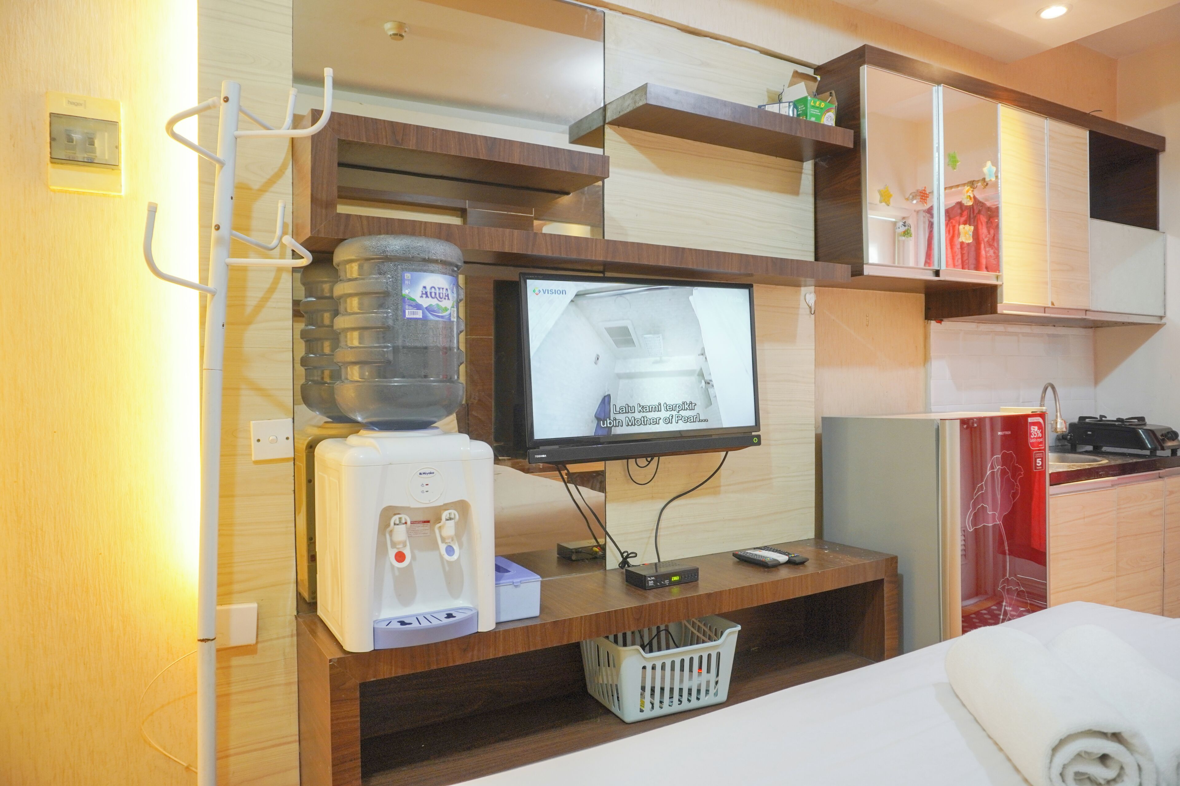 Un espacio habitable compacto con dispensador de agua, televisión y una pequeña zona de kitchenette.