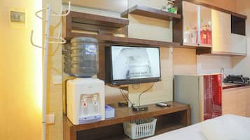 Un espacio habitable compacto con dispensador de agua, televisión y una pequeña zona de kitchenette.