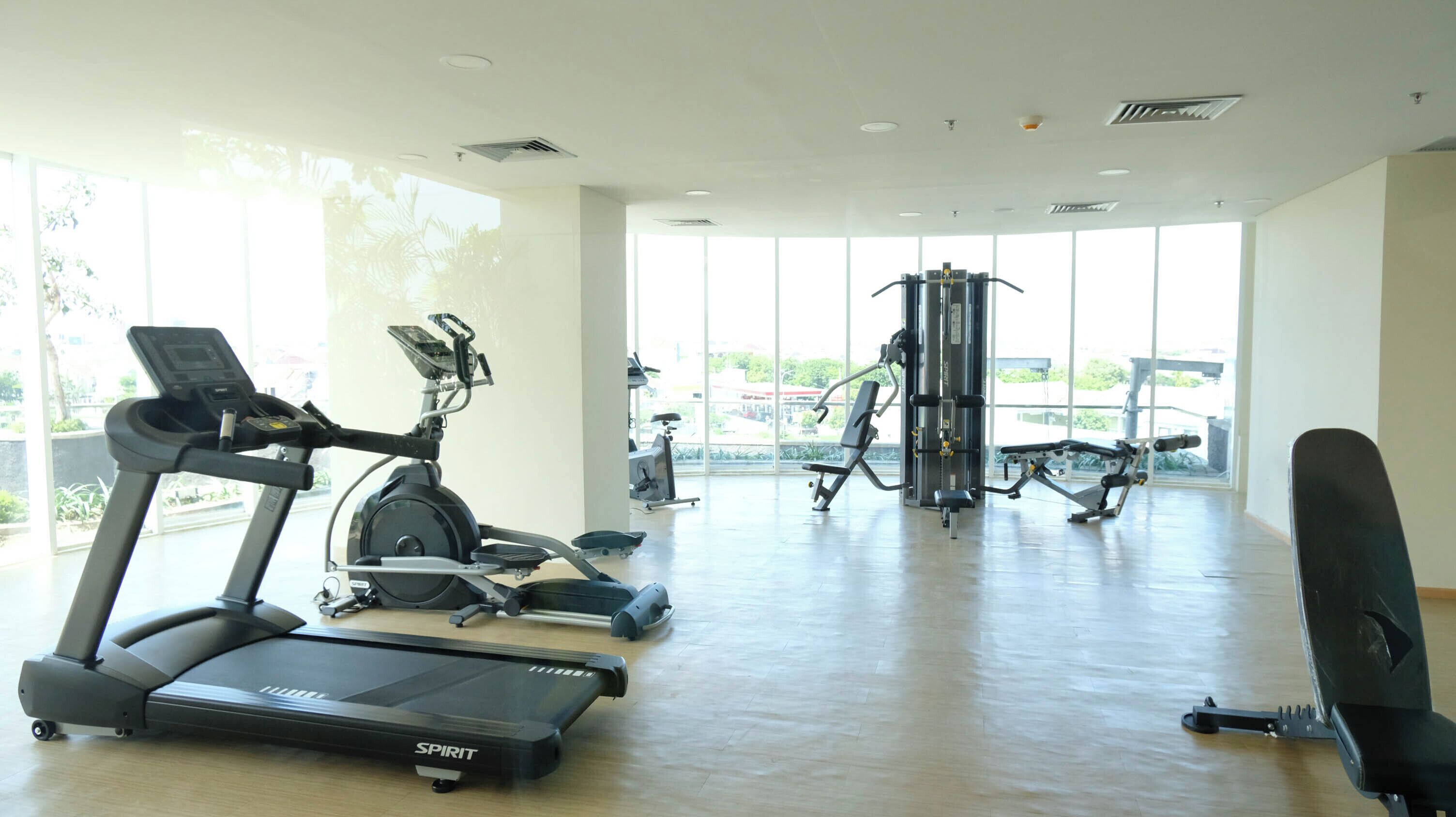 Une salle de sport équipée de machines de cardio, d’appareils de musculation et dotée de grandes fenêtres.