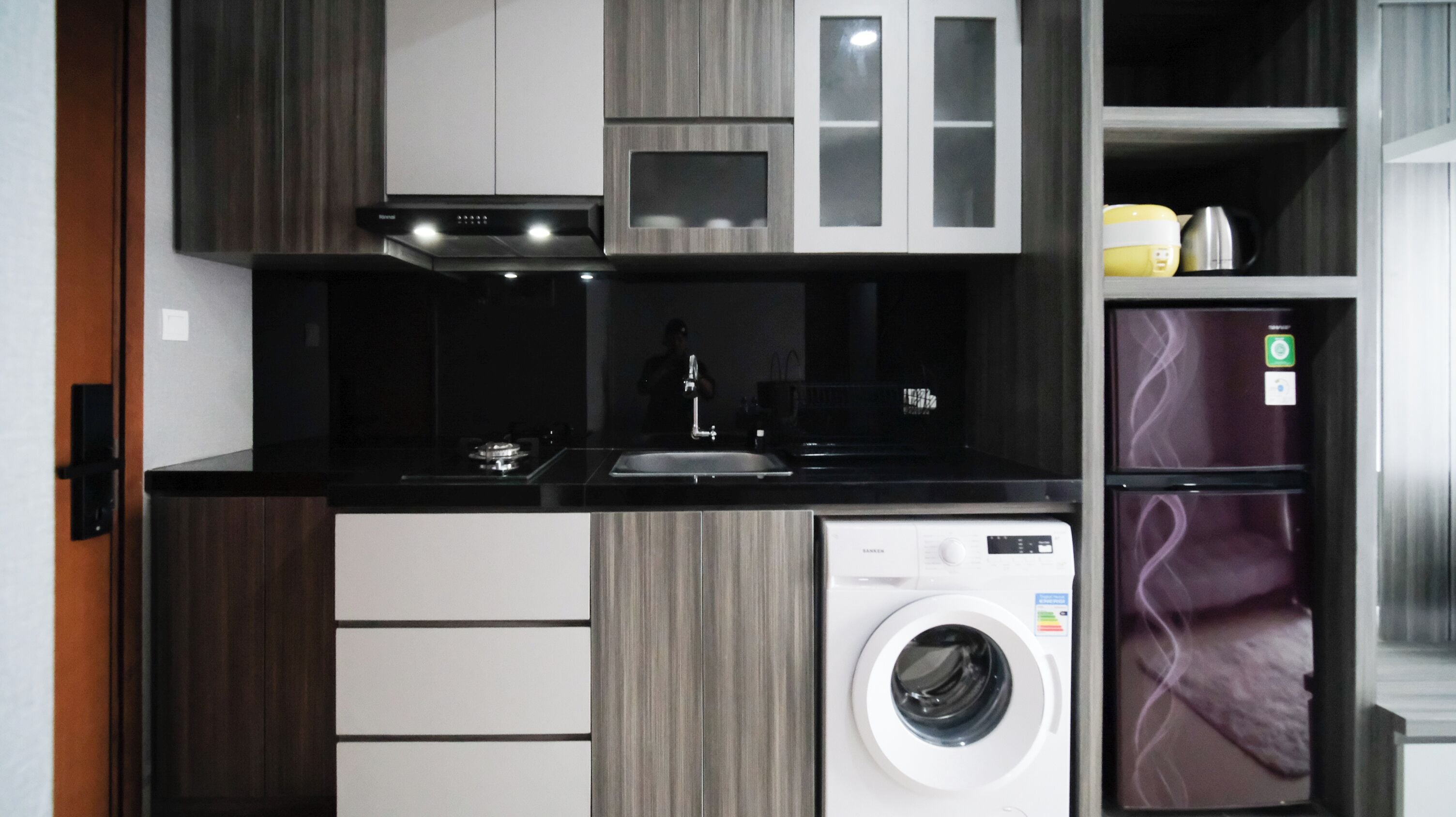 A compact kitchen with a built-in washer and dryer, a sink, and modern cabinetry.