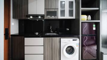 A compact kitchen with a built-in washer and dryer, a sink, and modern cabinetry.