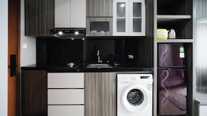 A compact kitchen with a built-in washer and dryer, a sink, and modern cabinetry. - Good Choice And Spacious 2Br At Grand Dharmahusada Lagoon Apartment (Surabaya)