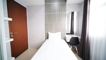 A hotel room with a bed, a desk, a chair, a door, and a curtain.