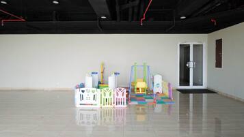 A spacious, empty room with a polished floor, a door, and colorful play equipment.