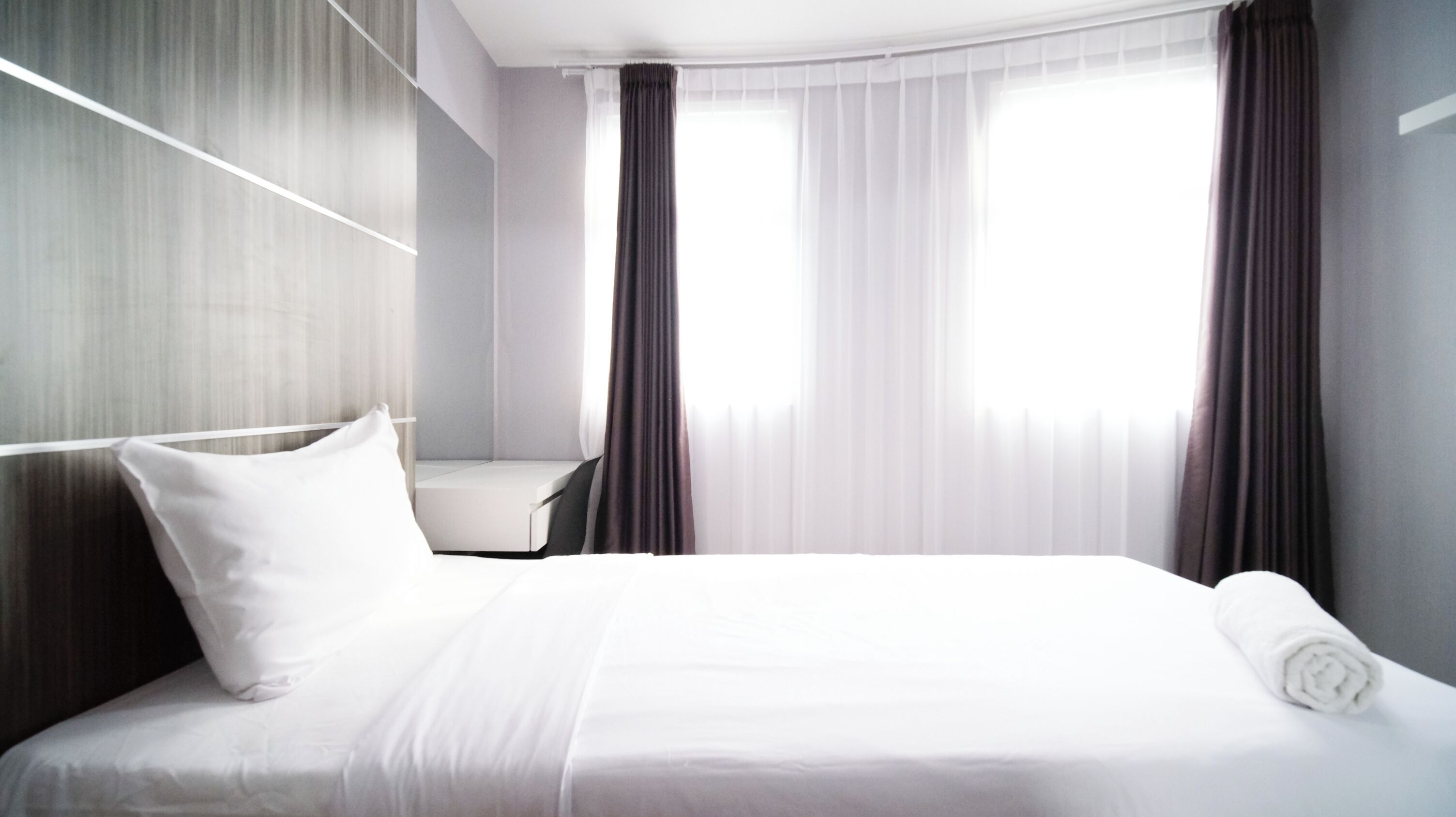Una habitación de hotel con cama, escritorio y ventana con cortinas.