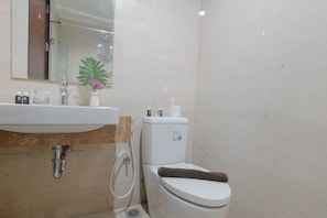 Ein Badezimmer mit Waschbecken, Spiegel, Toilette und Duschbereich.