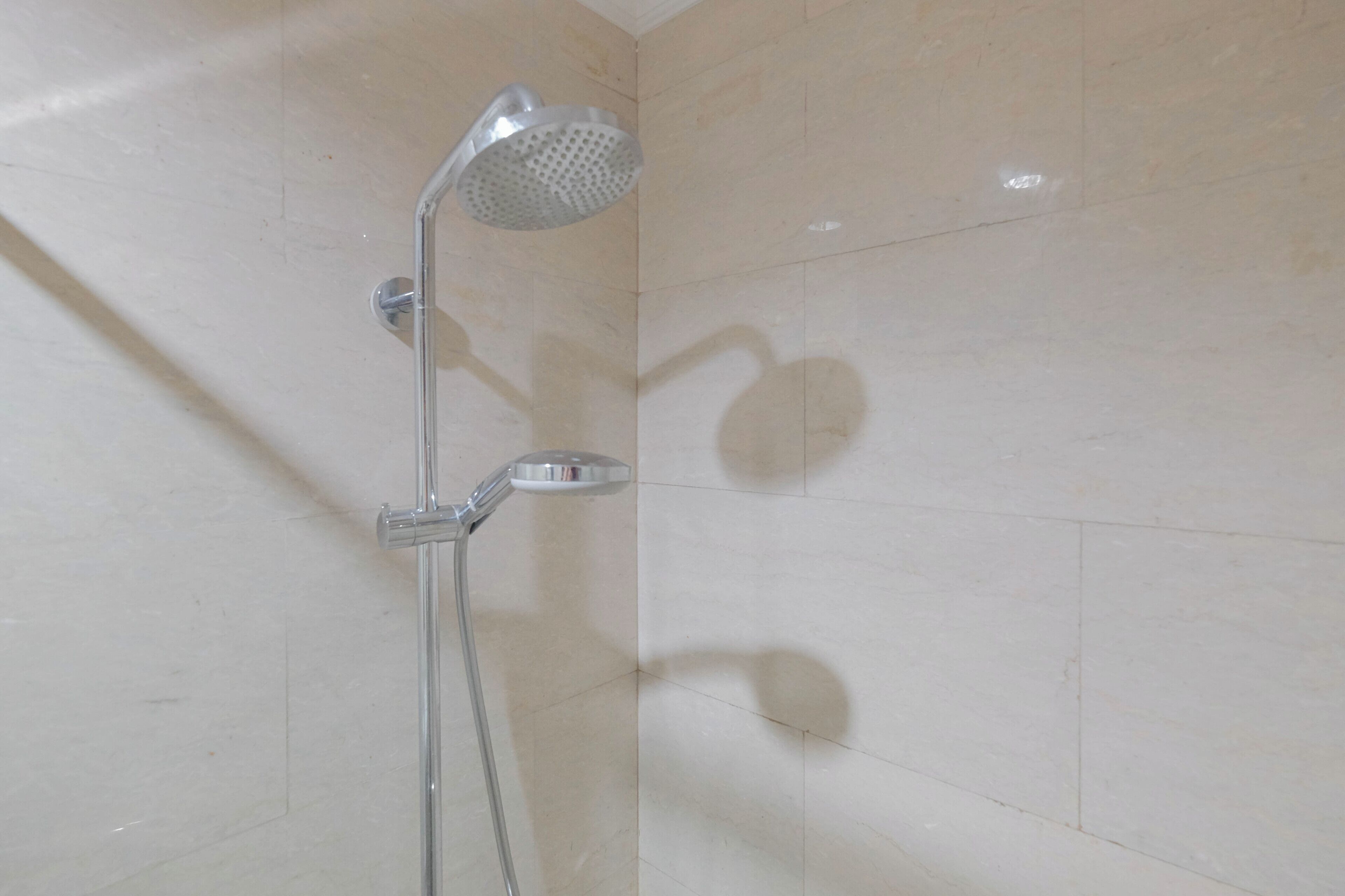 Una ducha con cabezal de ducha manual y otro fijo montado en la pared.