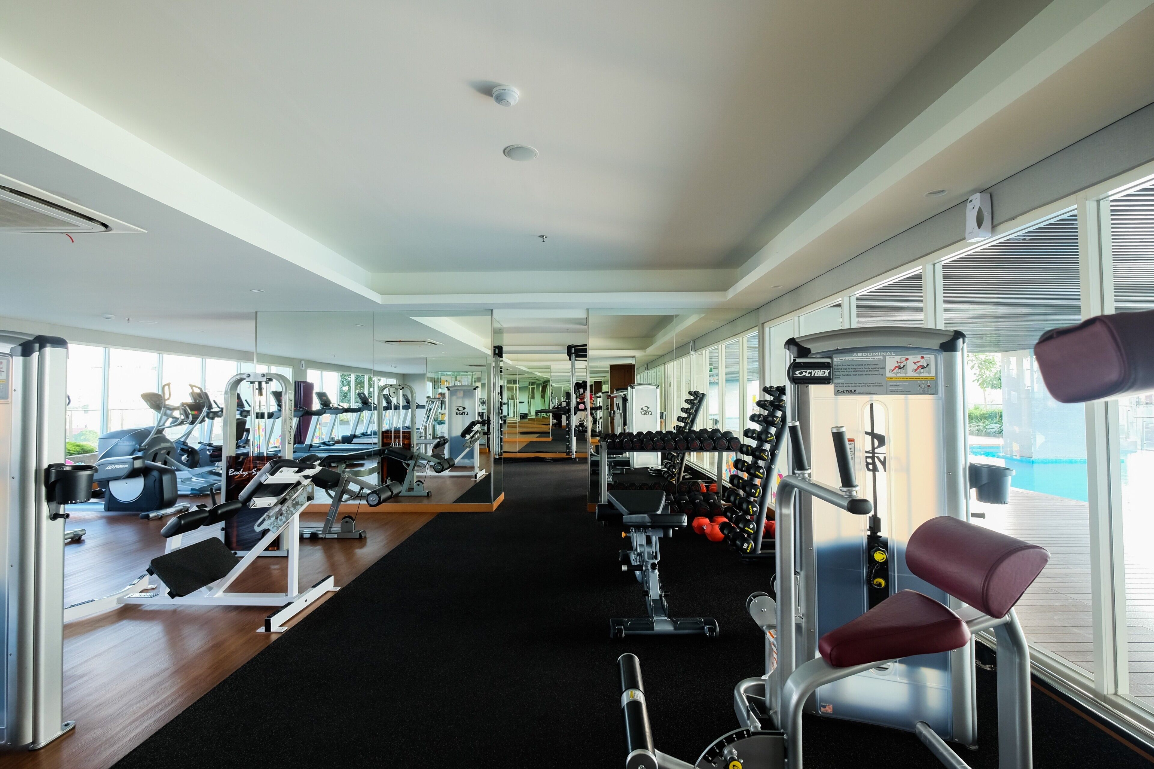 A gym with cardio machines, weight stations, and dumbbells.