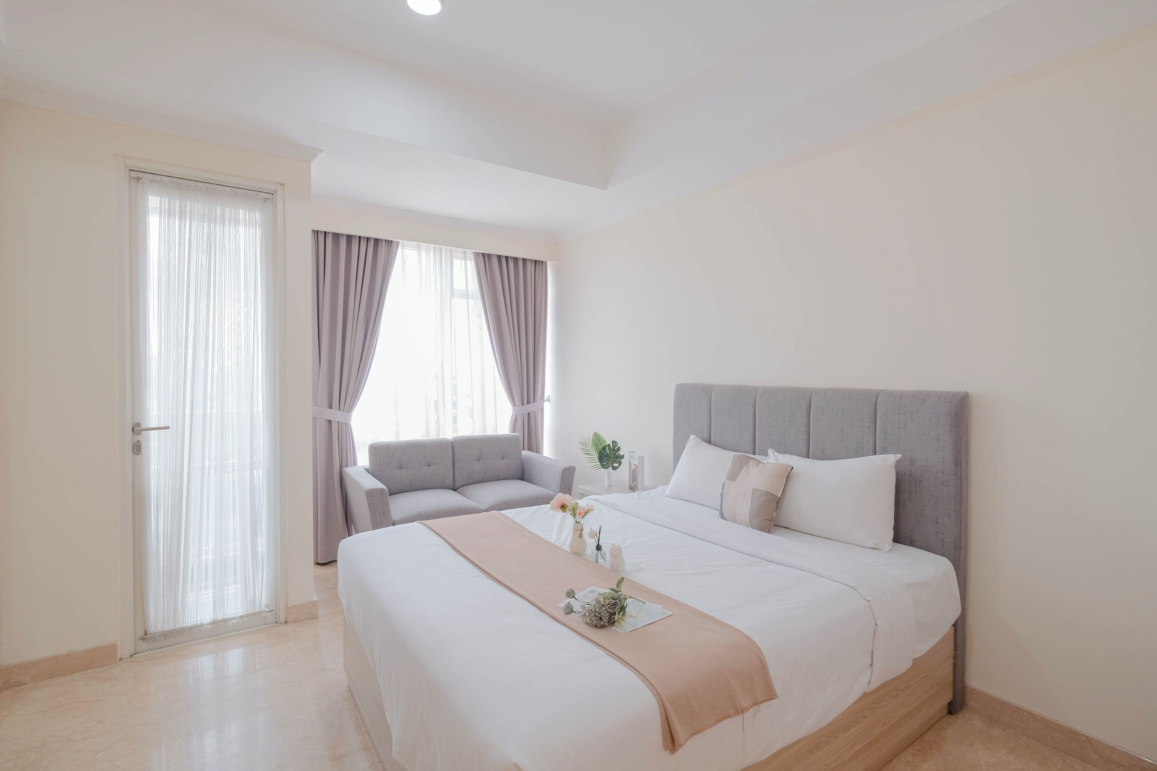 Una habitación de hotel con cama, sofá, ventana con cortinas y puerta.