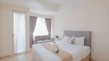 Una habitación de hotel con cama, sofá, ventana con cortinas y puerta.