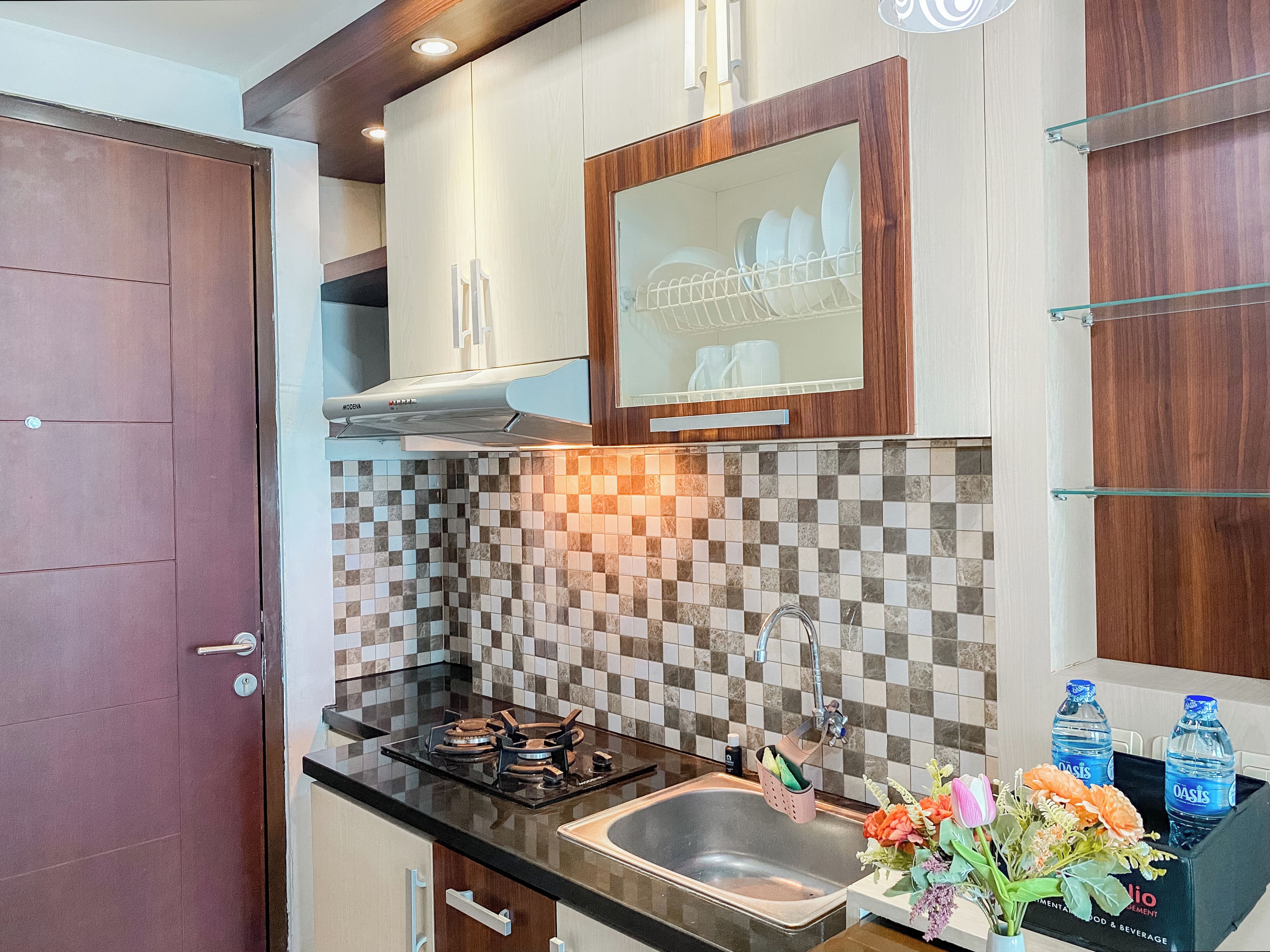 Una cocina con diseño moderno, que destaca por un salpicadero a cuadros, electrodomésticos de acero inoxidable y armarios de madera.