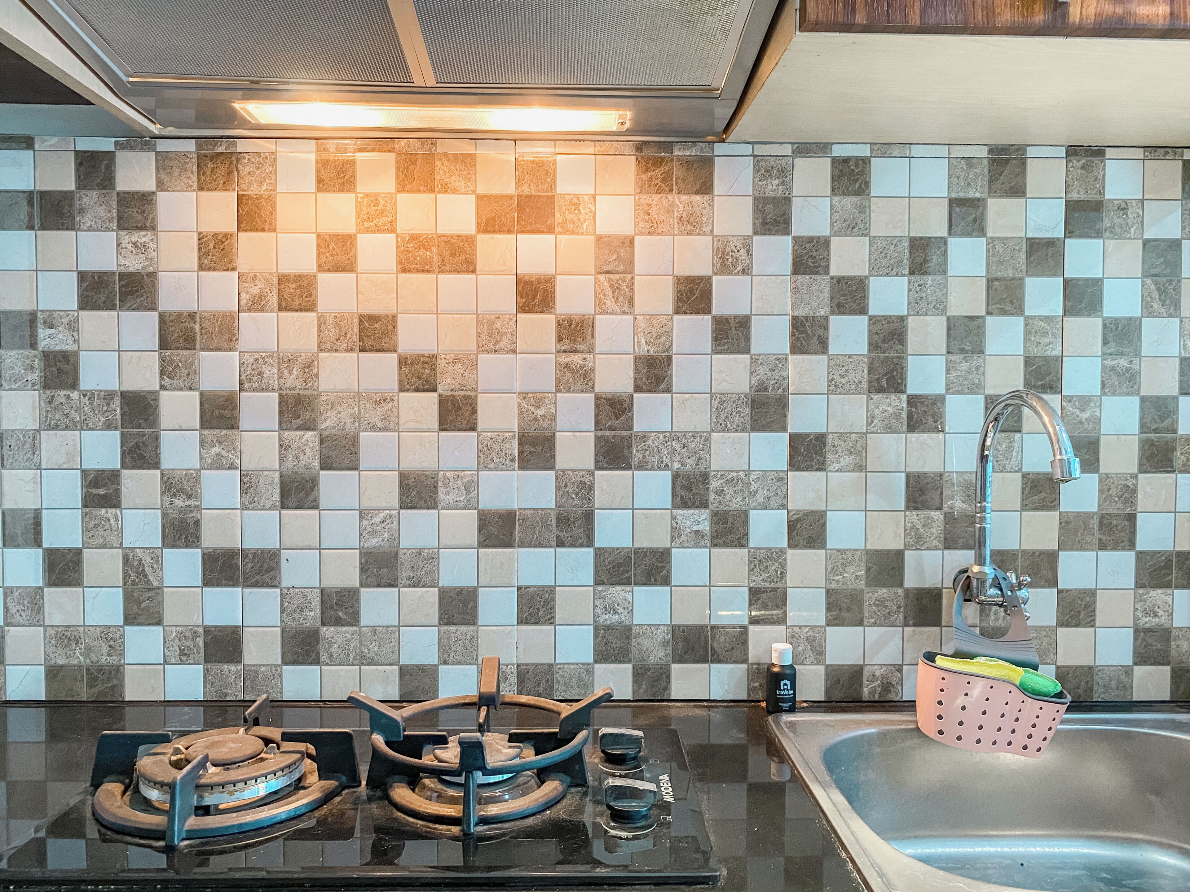A kitchen with a tiled backsplash, a gas stove, a sink, and a faucet.