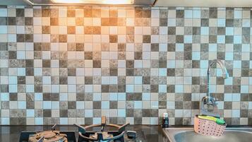 A kitchen with a tiled backsplash, a gas stove, a sink, and a faucet.