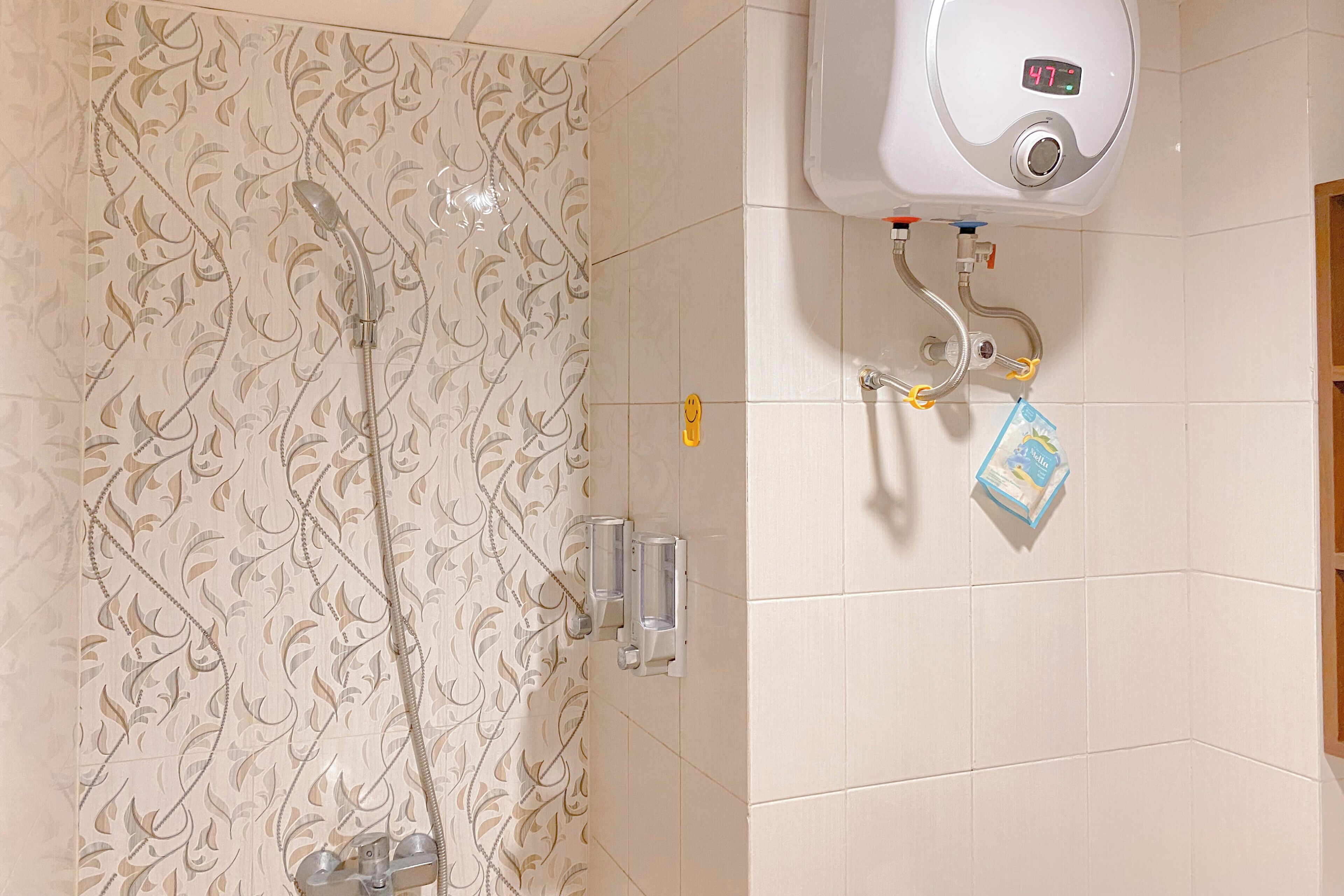 Une salle de bain équipée d’une douche, d’un sèche-mains et d’un distributeur de savon.